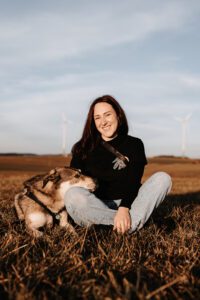 Lena sitzt bei Tinka am Boden